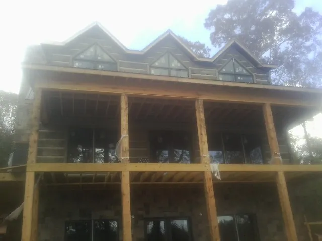 Dormers and porch framing on a large log home under construction — Roof Coating work by our crew in Hull