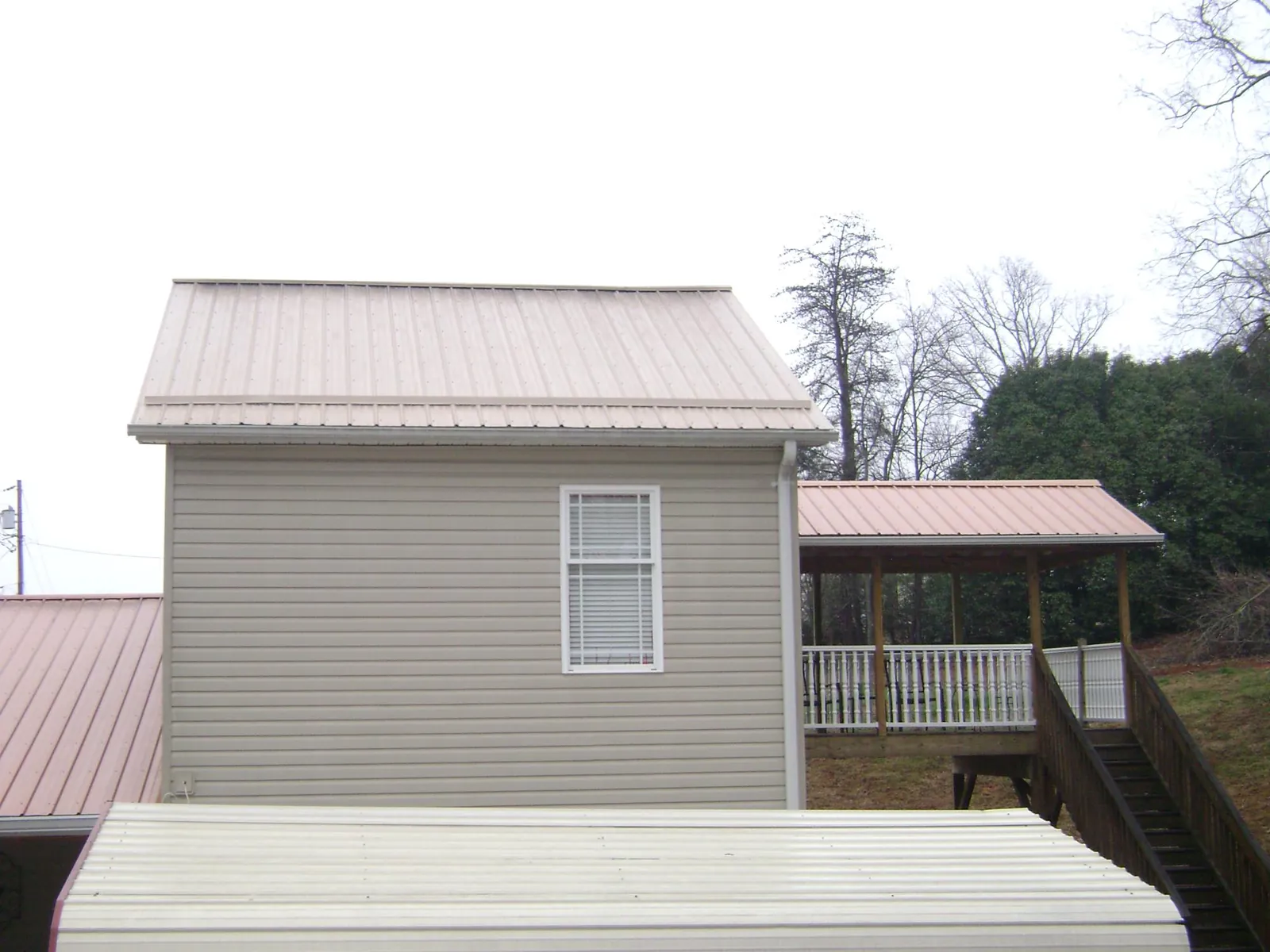 Tan metal roofs on a two story addition and attached porch, from a Roof Replacement job in Hull